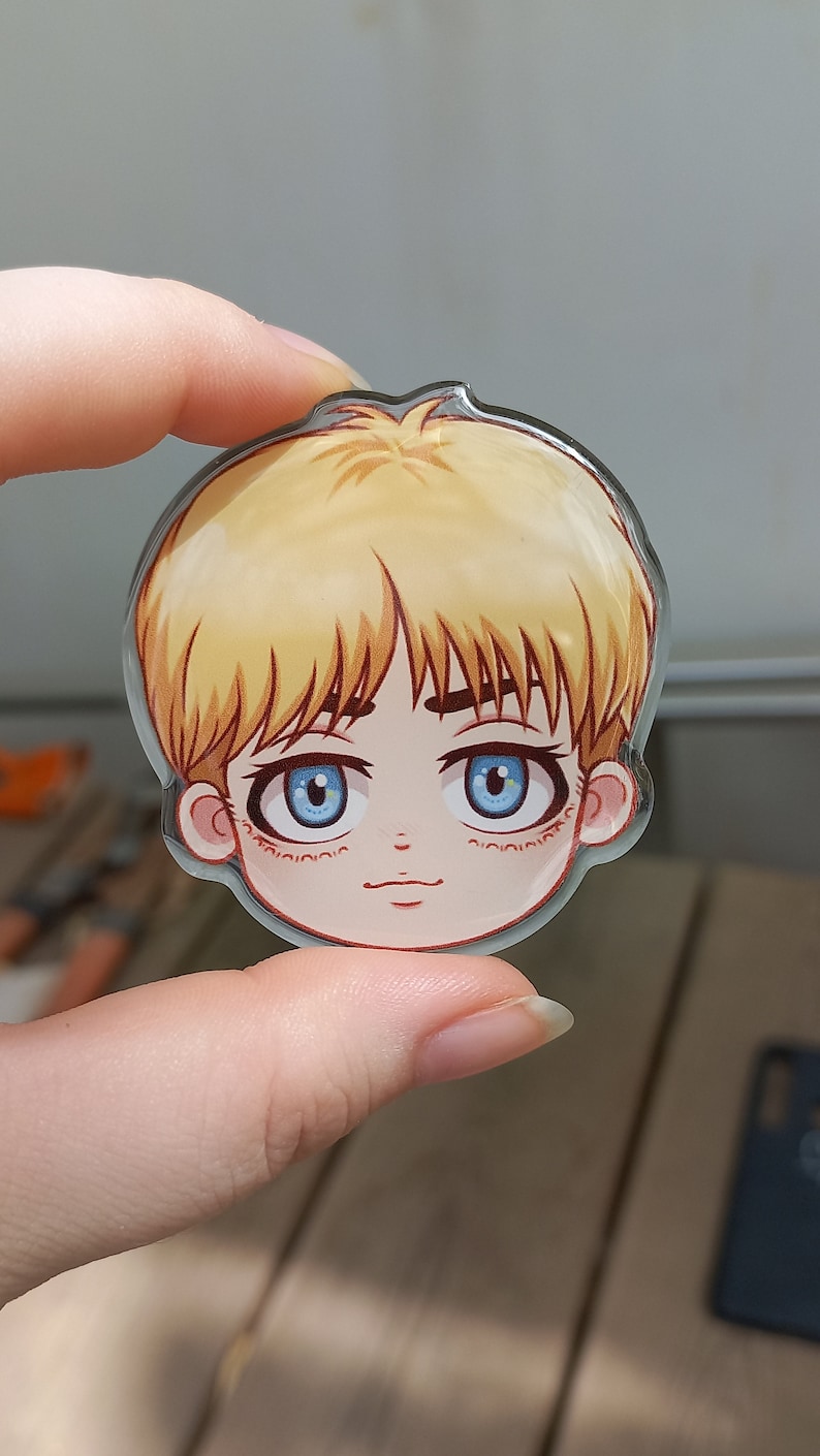Peut inclure: Un charme rond en acrylique transparent repr&eacute;sentant une illustration de dessin anim&eacute; d'une jeune personne aux cheveux blonds, aux yeux bleus et au teint rose clair. Le charme mesure environ 5 cm de diam&egrave;tre.