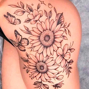 May include: Black and white tattoo design of sunflowers, butterflies, and a bee on a person's leg.