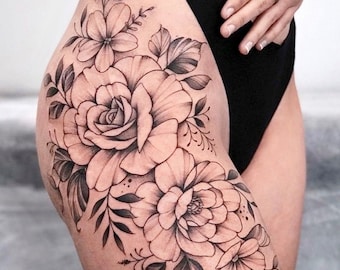 May include: Black and white floral tattoo design on a person's thigh. The tattoo features a large rose with leaves and smaller flowers.