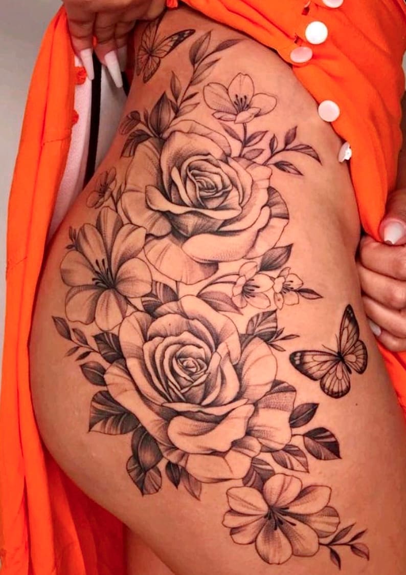 May include: A black and white tattoo design of roses and a butterfly on a person's hip.