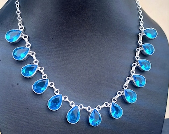 May include: A silver necklace with a chain and teardrop-shaped blue gemstones.