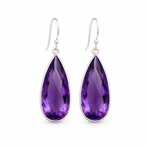 May include: A pair of drop earrings featuring faceted, pear-shaped purple amethyst gemstones set in polished silver-toned metal. Each earring hangs from a curved silver-toned hook, showcasing a deep violet hue and a clear, reflective surface.