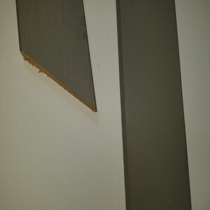 May include: Two vertical pieces of wood painted a dark gray color against a white background.