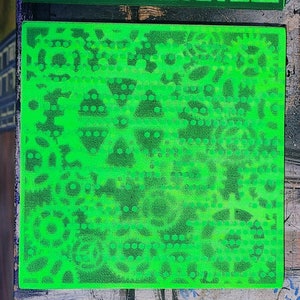 May include: Three green square tiles with different patterns of small circles and shapes. The tiles are made of a textured material and have a slightly raised surface.