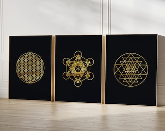 May include: Three black framed prints with gold geometric designs on a light wood floor. The designs are a flower of life, a metatron's cube, and a sri yantra.