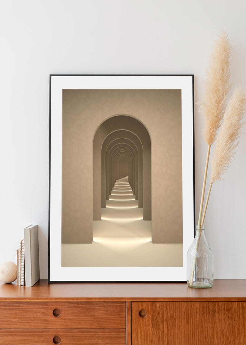 May include: A framed print of a hallway with a series of arches leading to a vanishing point. The walls and arches are a light beige color, and the floor is a lighter beige. The hallway is lit by a soft, warm light.