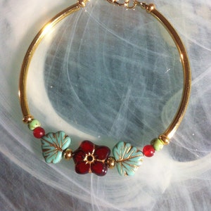 Bracelet of flower and glass leaves surrounded by small Czech beads and mounted on gold-plated tubes and closed with a carabiner