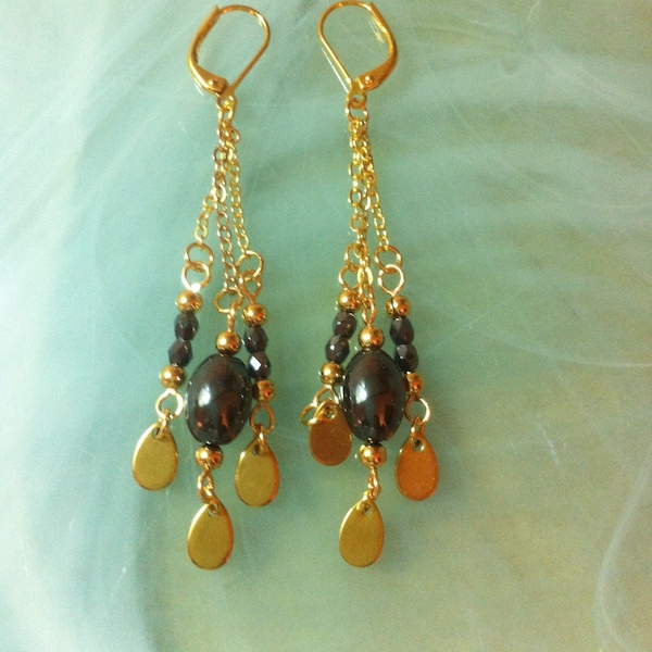 Boucles d'oreilles longues et bohèmes assorties au collier du même style et composées d'Hématites en tonneau, de perles facettées et dorées