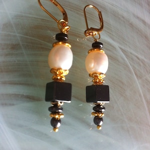 Earrings composed of freshwater pearls surrounded by gold-plated cups, fine Hematite stones of different shapes, square, ring and round