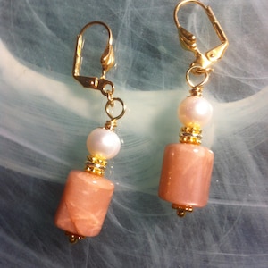 Earrings with natural Sunstone barrel and topped with golden beads and a freshwater pearl on a shell hook