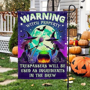 May include: A purple and black Halloween garden flag with a warning sign that reads "Warning Witch Property Trespassers Will Be Used As Ingredients In The Brew". The flag features two witches stirring a cauldron under a full moon.