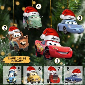 May include: A collection of eight Christmas tree ornaments featuring various cartoon car characters from the movie Cars, each wearing a red and white Santa hat with a customizable name tag area. The ornaments include a red race car, a brown tow truck, a light blue sports car, a green van, and other vehicle characters.
