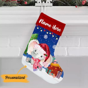 May include: A blue Christmas stocking with a cute cartoon elephant wearing a Santa hat and a pink scarf. The stocking has a red cuff with the text "Name Here" in white.