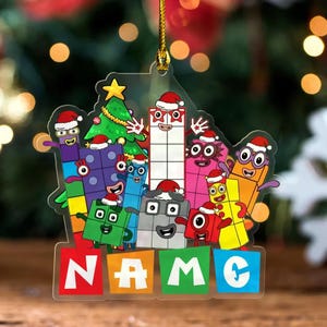 May include: A clear acrylic Christmas ornament featuring a group of colourful Numberblocks characters wearing Santa hats, arranged around a green Christmas tree. Below the characters, four colourful blocks display the white text "NAME".