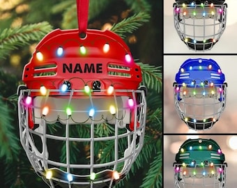 May include: A red hockey helmet ornament with a white cage and colorful lights. The helmet has the word "NAME" printed on the front.