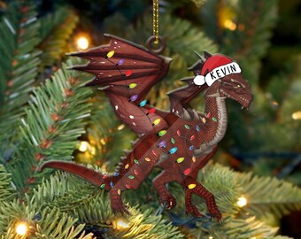 May include: A red dragon Christmas ornament with a Santa hat that says "KEVIN" on it. The dragon is decorated with colorful lights.