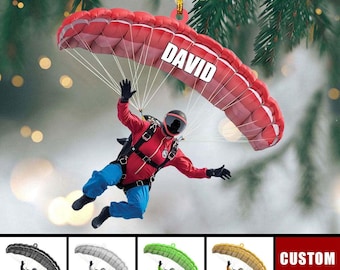 Può includere: Un ornamento a forma di paracadute rosso e bianco con un paracadutista appeso ad esso. Il paracadute ha il nome "DAVID" stampato su di esso. L'ornamento è un ottimo regalo per gli appassionati di paracadutismo.