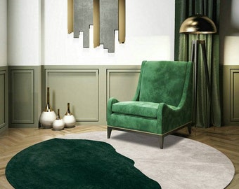 May include: A round rug with a dark green and light gray design sits on a wooden floor. A green armchair with wooden legs and gold accents is next to the rug. The room has green walls and a gold floor lamp.