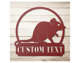 May include: A burgundy metal sign featuring a rat silhouette within a circular frame. The sign includes a rectangular banner with the words "CUSTOM TEXT" cut out. The background is a light wood panel.