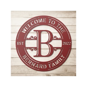 May include: A red metal family sign with the text "WELCOME TO THE" at the top, "EST 2022" on the left and right, and "BERNARD FAMILY" at the bottom. A large letter "B" is in the center.