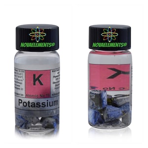 Könnte beinhalten: Eine kleine Glasflasche mit schwarzem Deckel, die eine Probe von Kalium enthält, einem weichen, silbrig-weißen Alkalimetall. Das Flaschenetikett enthält das Elementsymbol "K", die Ordnungszahl 19 und den Namen "Kalium".