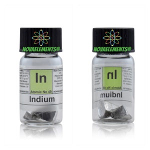 Puede incluir: Dos peque&ntilde;os frascos de vidrio que contienen muestras del elemento Indium. Los frascos est&aacute;n etiquetados con el s&iacute;mbolo del elemento "In" y el n&uacute;mero at&oacute;mico 49. Los frascos est&aacute;n sobre un fondo blanco.