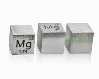 May include: Three silver cubes with the chemical symbol and atomic number for magnesium (Mg, 12) engraved on each side. The cubes are arranged in a row on a white background.
