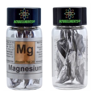 Può includere: Una bottiglia di vetro trasparente con un tappo nero che contiene un campione di magnesio metallico. L'etichetta sulla bottiglia riporta "NOVAELEMENTS®" e include il simbolo chimico "Mg" e il numero atomico 20. L'etichetta riporta anche "Magnesio".