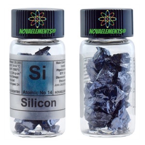 Op de afbeelding: Een doorzichtige glazen fles met een zwarte dop die een monster silicium bevat. Het etiket op de fles luidt "NOVAELEMENTS®" en "Silicon Atomic No 14".