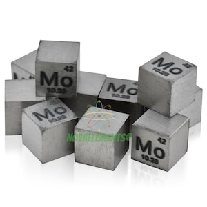 May include: A group of small, silver-colored cubes with the chemical symbol "Mo" and atomic number "42" printed on each side. The cubes are arranged in a pile on a white background.