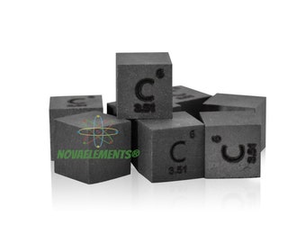 May include: A close-up of a pile of small, black, cube-shaped samples of carbon. Each cube has the chemical symbol "C" and the atomic number "6" printed on it. The cubes are arranged in a loose pile on a white background.