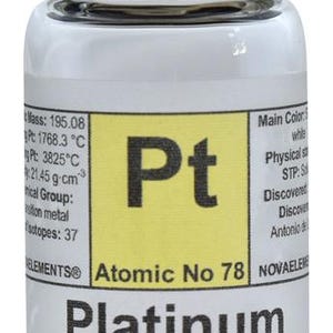 May include: A clear glass bottle with a black lid containing a small silver ball. The label on the bottle reads "Pt Platinum Atomic No 78" and includes information about the element's atomic mass, melting point, boiling point, density, and group.