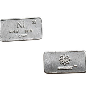 Könnte beinhalten: Zwei silberne Metallbarren, einer mit dem chemischen Symbol und Namen für Nickel, Ni, und der andere mit einem Atomsymbol und dem Wort "Elemente".