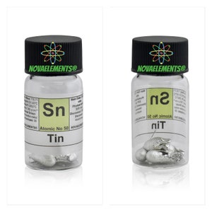May include: A clear glass jar with a black lid containing a small sample of tin metal. The jar has a white label with the text "Sn Atomic No 50 Tin" and other information about the element.