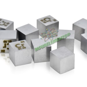 May include: A group of small, silver-colored cubes with the chemical symbol and atomic number for Chromium (Cr) inscribed on each cube. The cubes are arranged in a scattered pattern on a white background.