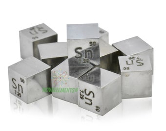 May include: A group of silver-colored cubes with the chemical symbol "Sn" and the atomic number "50" engraved on each side. The cubes are arranged in a pile on a white background.
