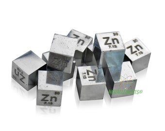 May include: A group of silver-colored zinc cubes, each with the chemical symbol "Zn" and atomic number "30" engraved on one side. The cubes are arranged in a pile on a white background.
