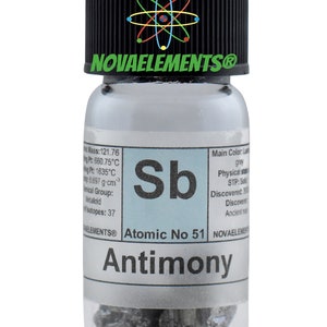 Pu&ograve; includere: Un piccolo flacone di vetro contenente un campione di antimonio, un elemento metalloide. Il flacone ha un tappo nero con il testo "NOVAELEMENTS&reg;" e un simbolo di atomo stilizzato. L'etichetta sul flacone include il simbolo dell'elemento "Sb", il numero atomico 51 e il nome "Antimonio".