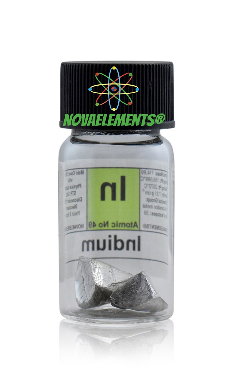 Puede incluir: Una botella de vidrio transparente con una tapa negra que contiene un peque&ntilde;o trozo de metal de Indio. La etiqueta de la botella tiene el s&iacute;mbolo del elemento "In" y el n&uacute;mero at&oacute;mico "49".