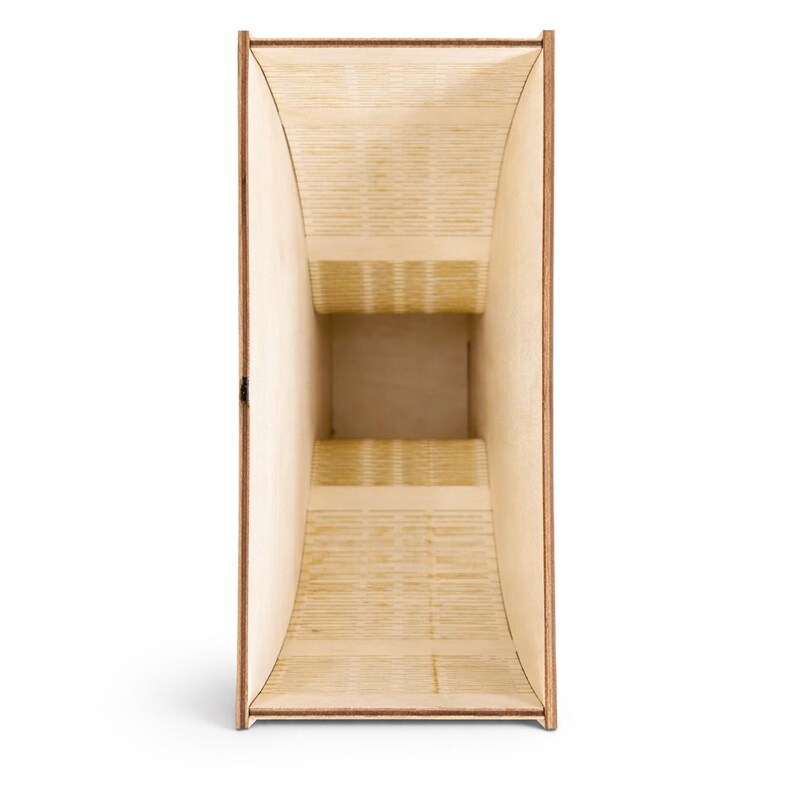 Puede incluir: Una caja de madera con un interior trapezoidal. La caja est&aacute; hecha de madera de color claro con un borde marr&oacute;n m&aacute;s oscuro. El interior tiene un dise&ntilde;o escalonado, creando un efecto visual &uacute;nico. La caja est&aacute; vac&iacute;a y se mantiene en posici&oacute;n vertical.