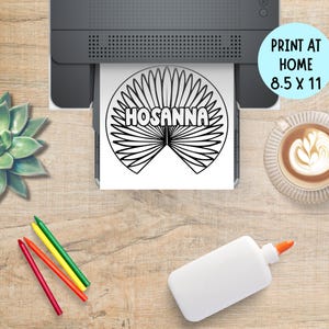 May include: A black and white "Hosanna" printable design is being printed from a printer. The design is on an 8.5 x 11 inch sheet of paper. The image also includes crayons, glue, and a cup of coffee.