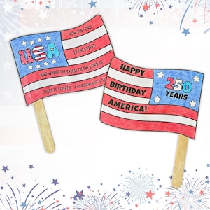 Pode incluir: Duas bandeiras de papel de mão em palitos de madeira, coloridas em vermelho, branco e azul. Uma bandeira apresenta o texto USA e 2 Corinthians 3:17. A outra bandeira exibe o texto Happy Birthday America! 250 Years, com padrões de estrelas e listras.