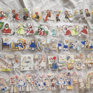 May include: Clear decorative tape rolls with illustrations of children, rainbows, and whimsical scenes. The tape features images of girls in dresses, boys, and fairytale elements. Ideal for scrapbooking and crafts.