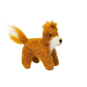 May include: A small needle-felted dog figurine crafted from textured ginger-orange wool fibres. The dog features a white muzzle, a black nose, and dark eyes, with a bushy tail extending upwards and a tuft of fur standing upright on its head.