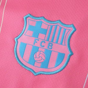 K&ouml;nnte beinhalten: Nahaufnahme eines pinkfarbenen Stoffes mit einem hellblauen Emblem. Das Emblem zeigt ein Schilddesign mit den Buchstaben "FCB" und einem Fu&szlig;ball. Das Schild ist hellblau umrandet.