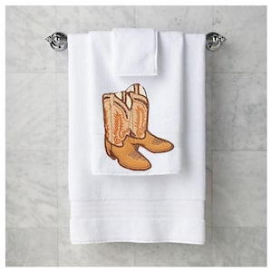 Op de afbeelding: Witte badhanddoek met geborduurde bruine cowboylaarzen.