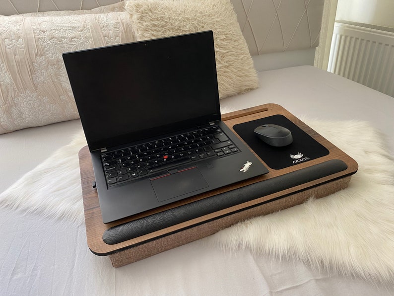 Może przedstawiać: Drewniany stojak na laptopa z wbudowanym podparciem nadgarstka i czarną podkładką pod mysz z nadrukiem "AGOLR". Na stojaku znajduje się laptop i bezprzewodowa mysz.