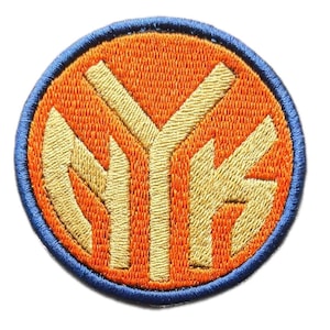 Può includere: Una toppa ricamata circolare che presenta le lettere NYK in filo dorato centrate su uno sfondo arancione vivace. Il design è racchiuso da un bordo spesso cucito in blu scuro, creando un contorno netto e definito per questo accessorio.