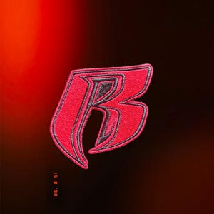 May include: An embroidered patch featuring a stylized letter B in vibrant red thread with dark grey outlines. The design has sharp, angular edges and a bold, modern aesthetic. The embroidery texture is visible throughout the letter's surface.
