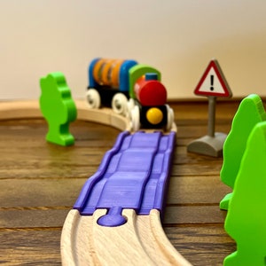 May include: A wooden toy train set with a purple track, a red and yellow train engine, and a green tree. The train is going around a curve in the track.